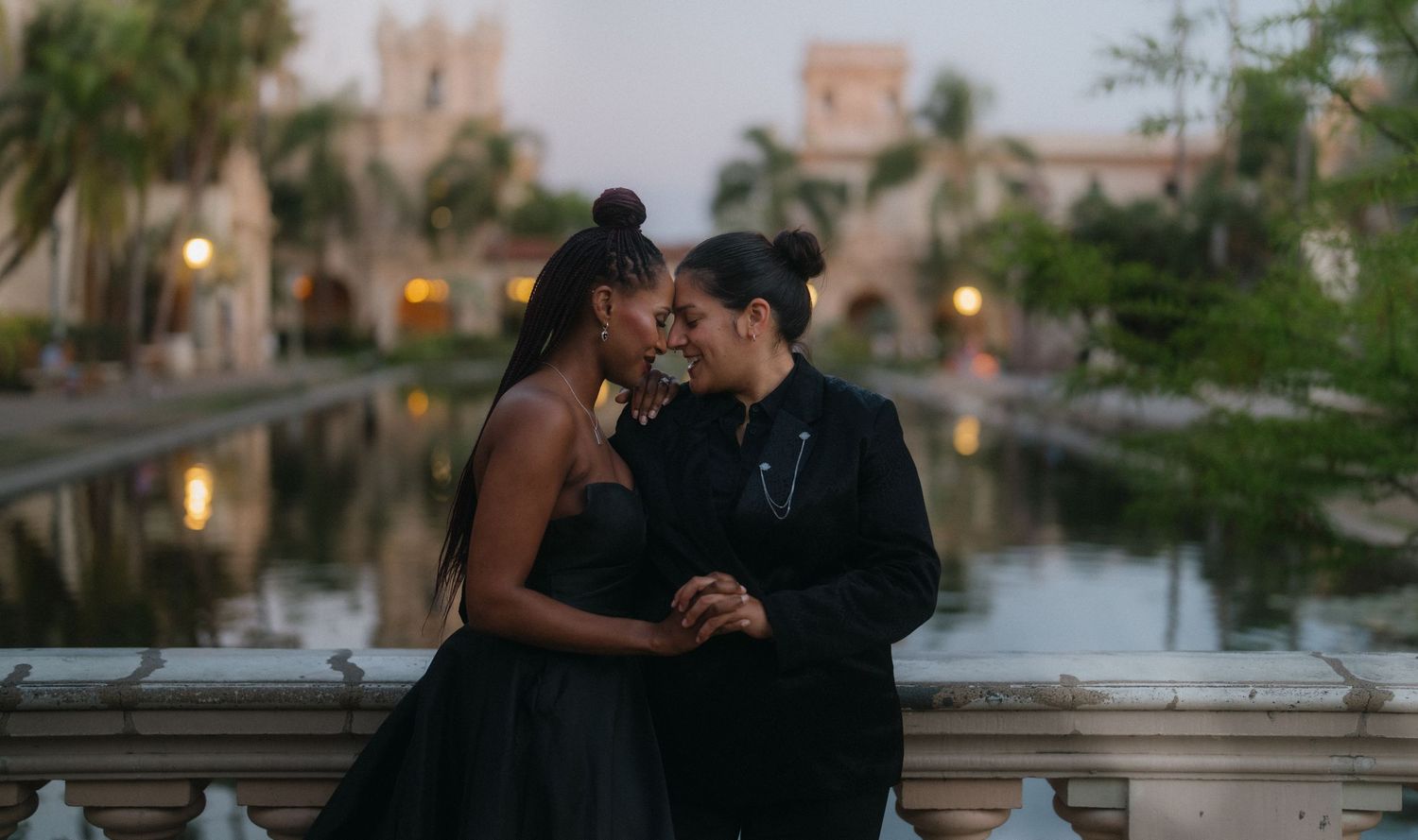 Couple sharing an intimate moment at dusk beside a reflective pool at Balboa Park in San Diego.