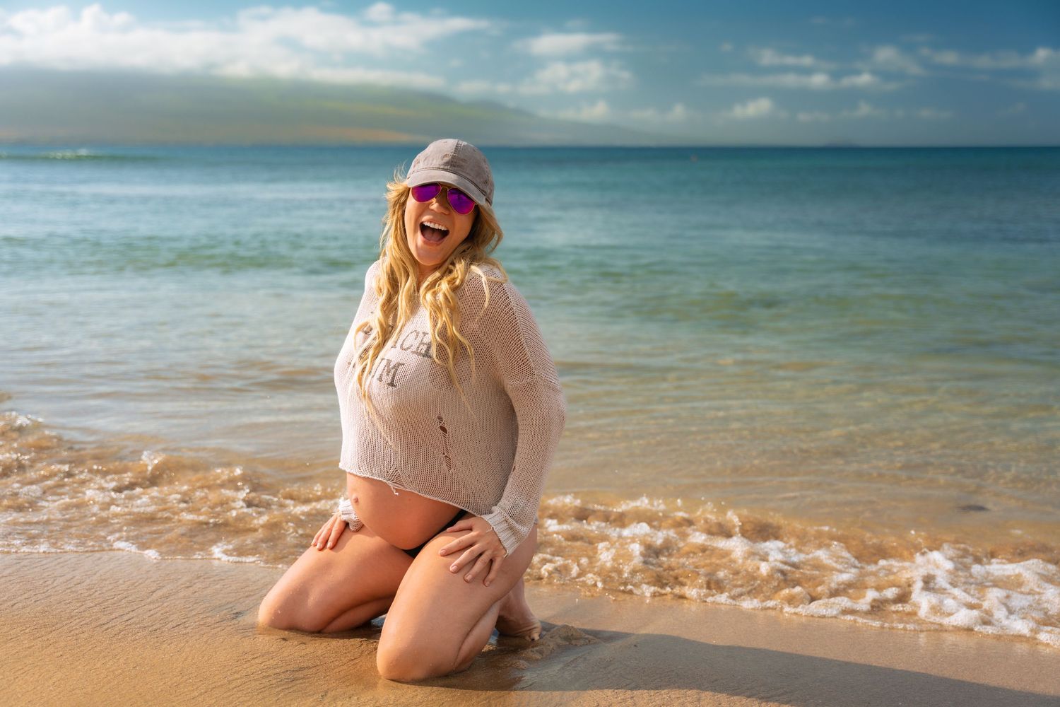 Playful beach photography session at water's edge during bright daylight.