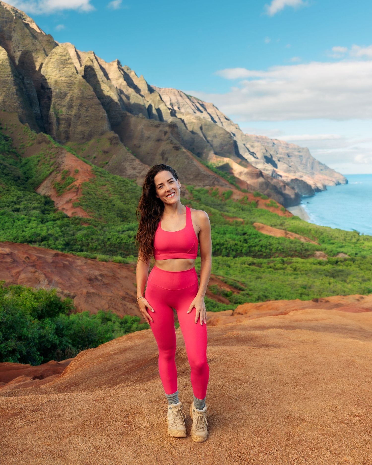 Scenic red dirt hiking trail with dramatic mountain cliffs and blue skies in Hawaii. kalalau trail kauai
