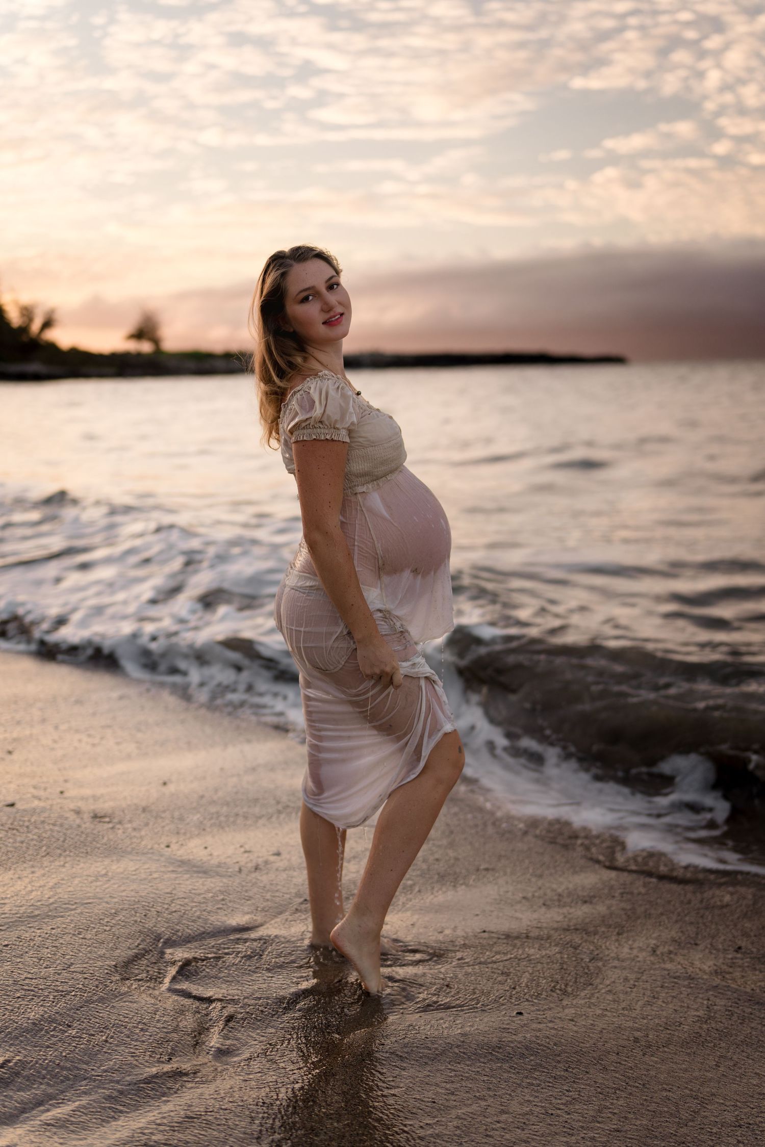 Sunset beach photoshoot with waves crashing on sandy shore.