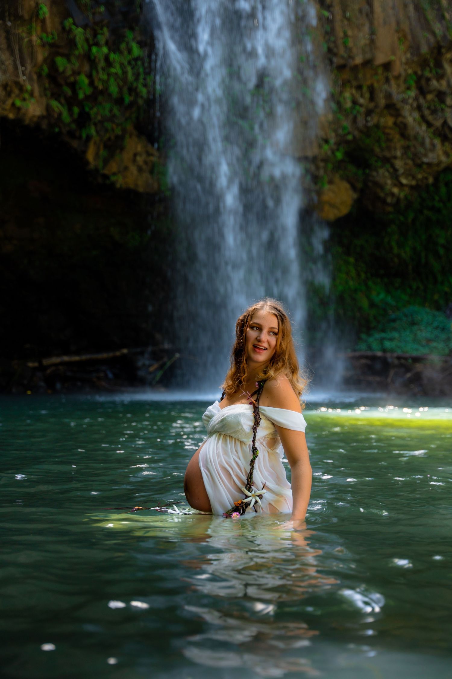White-dressed figure enjoying natural pool beneath majestic waterfall.