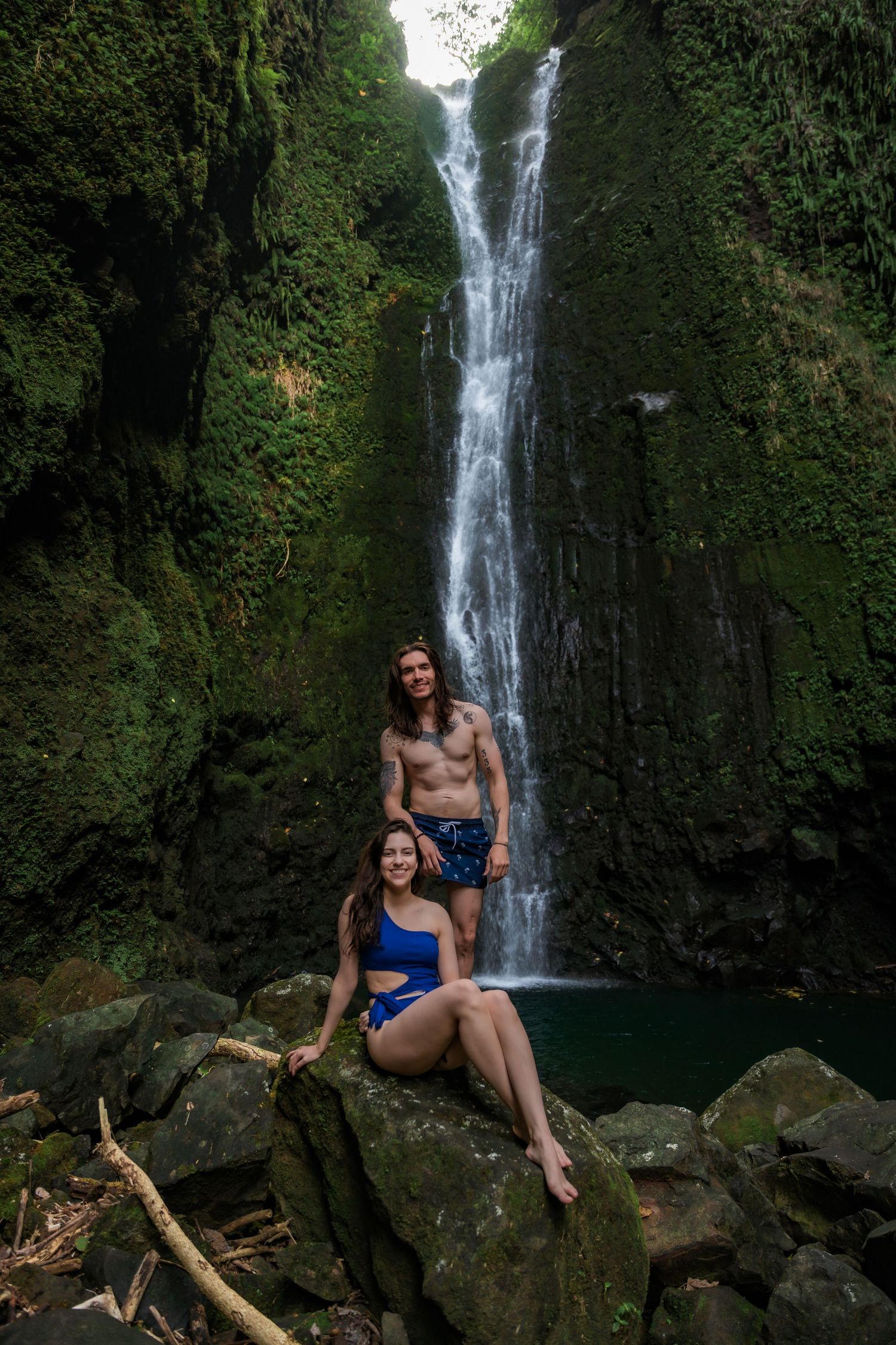 Scenic waterfall creates perfect backdrop for swimming and relaxation on volcanic rocks.