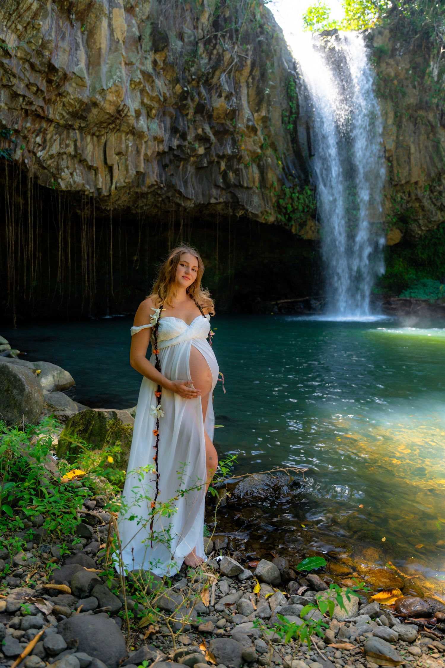 A serene maternity portrait against a majestic waterfall backdrop.