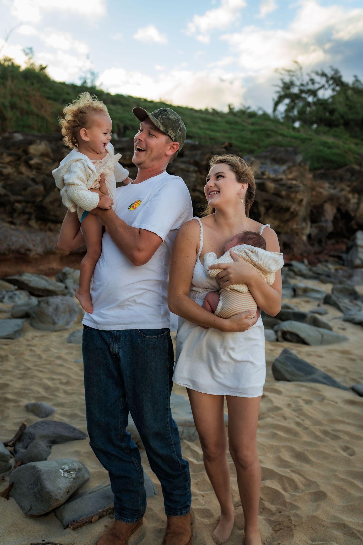 A family shares a joyful moment together on a beach with volcanic rocks in the background.