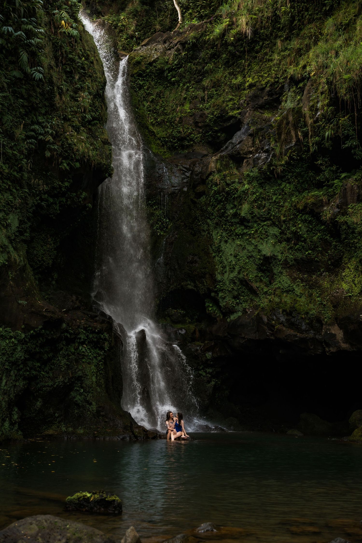 Cascading waterfall flows into a deep blue pool surrounded by verdant cliffs.