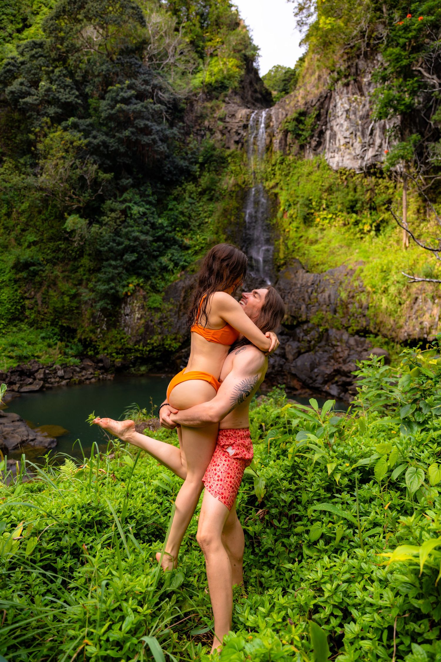 A playful moment captured at a scenic waterfall with lush greenery surrounding the scene.