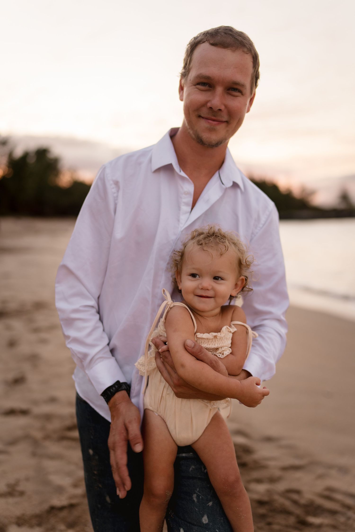 A playful beach moment captured during golden hour with the ocean in the background.