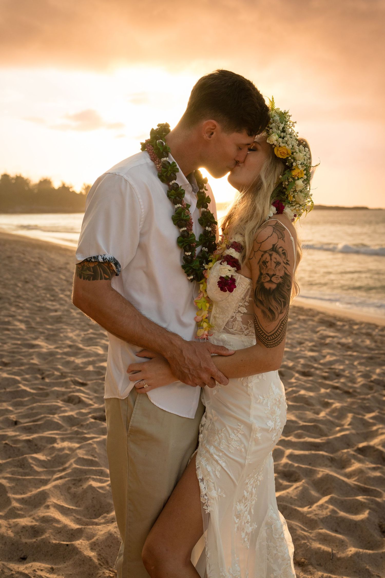 A romantic beach wedding portrait at sunset with traditional Hawaiian elements.