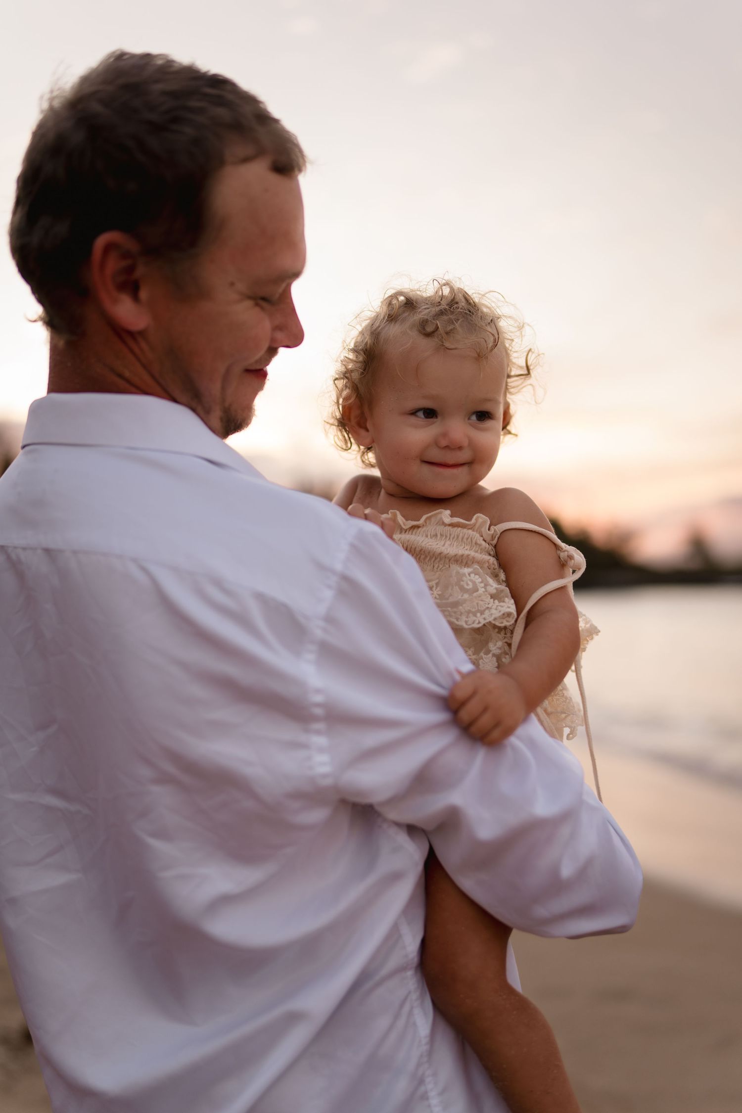 A tender moment between family members on the beach at sunset.