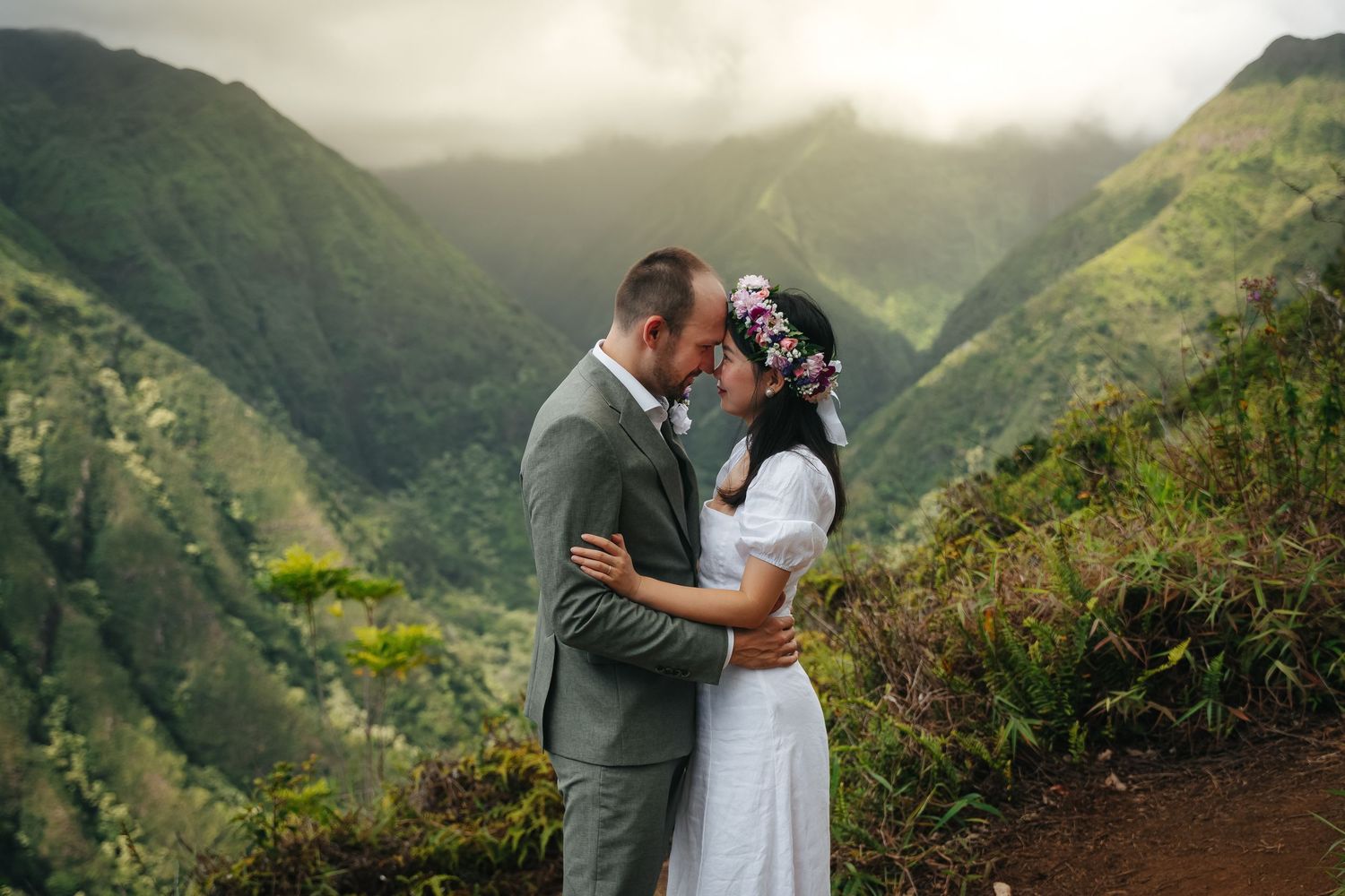 A romantic embrace between newlyweds on a misty mountain ridge.