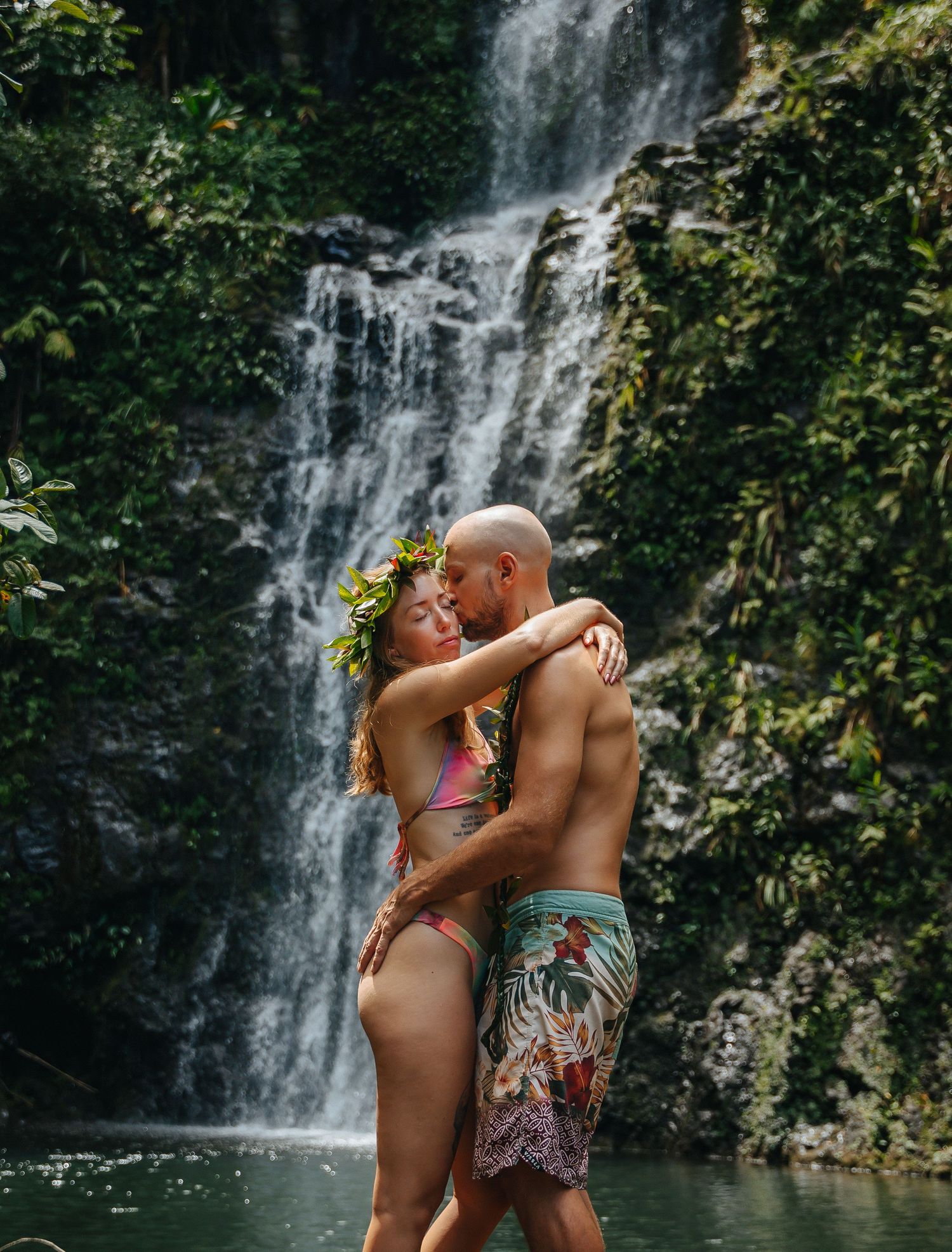 Intimate moment captured between couple at a tropical waterfall in Hawaii.