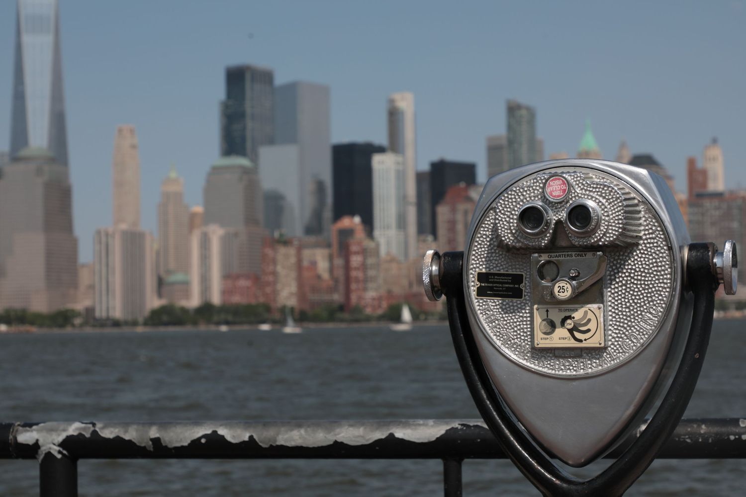 Tourist binocular viewer overlooking Manhattan skyline with One World Trade Center visible.