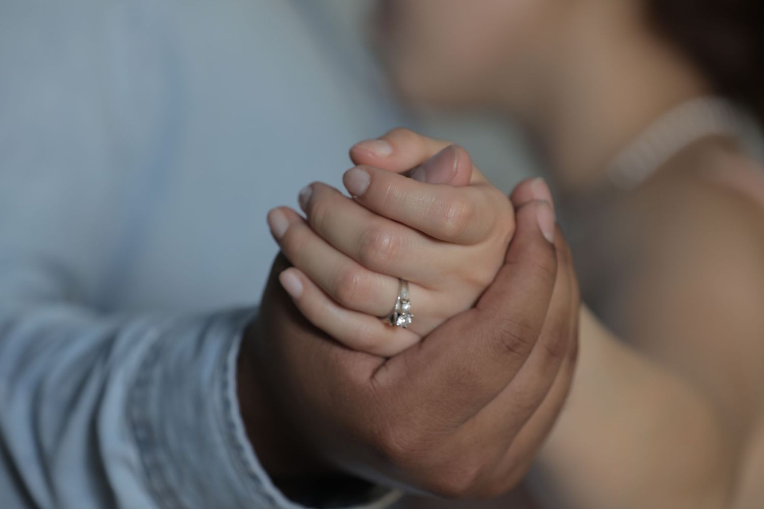 Close-up shot of clasped hands showing an engagement ring.