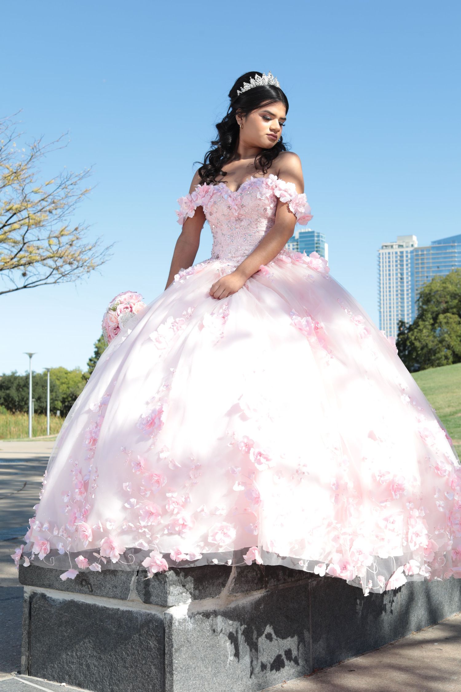 Pink princess ball gown with floral details photographed against urban backdrop.