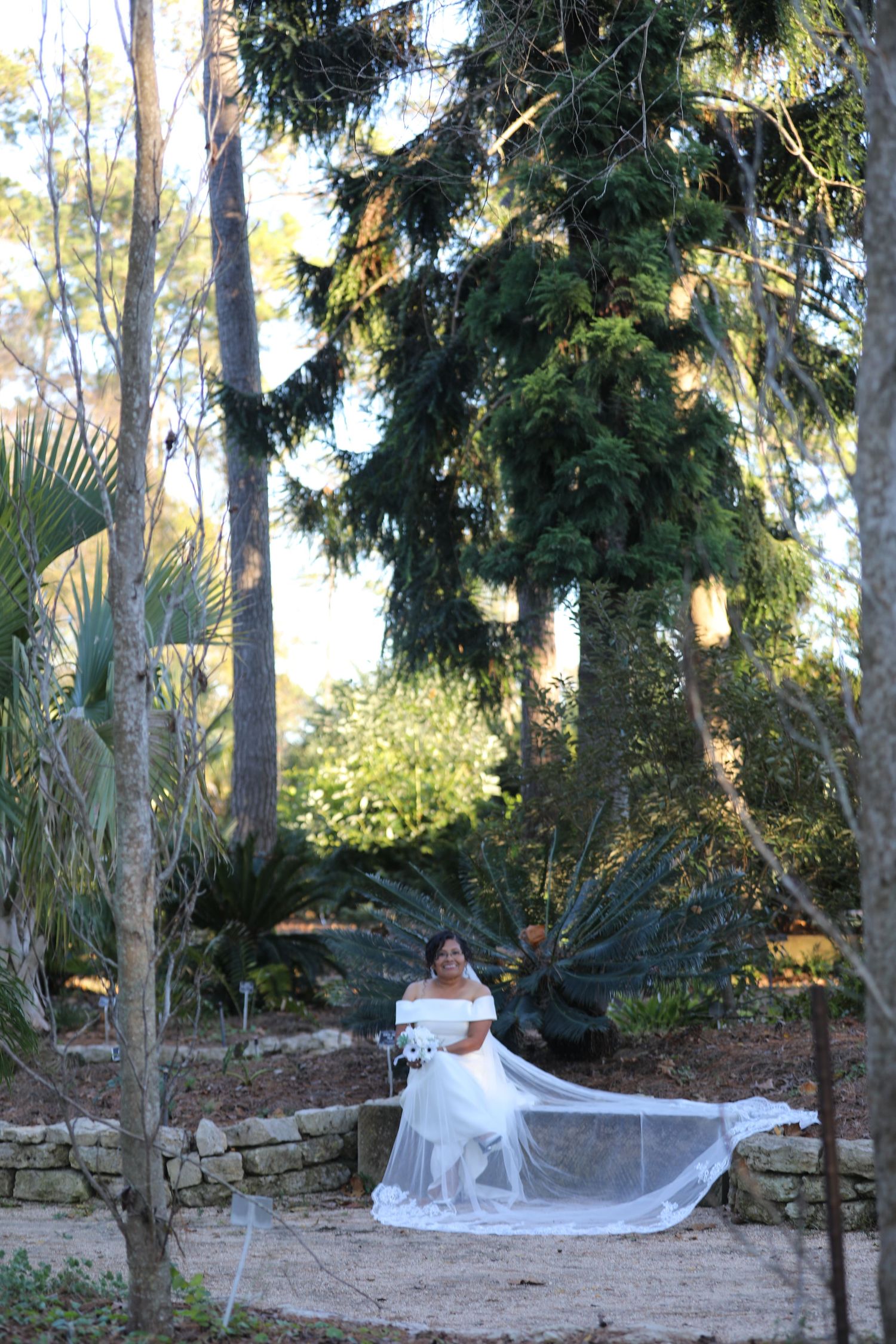 Elegant bridal portrait in a lush garden setting with flowing white dress.