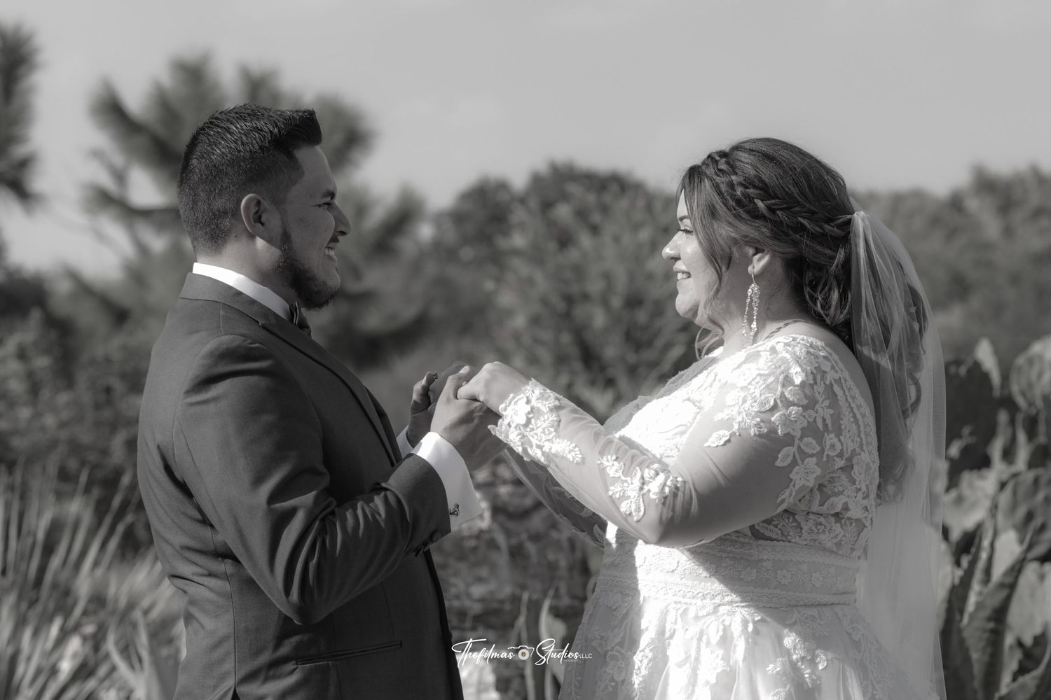 Black and white photo of a couple exchanging vows during an outdoor wedding ceremony.