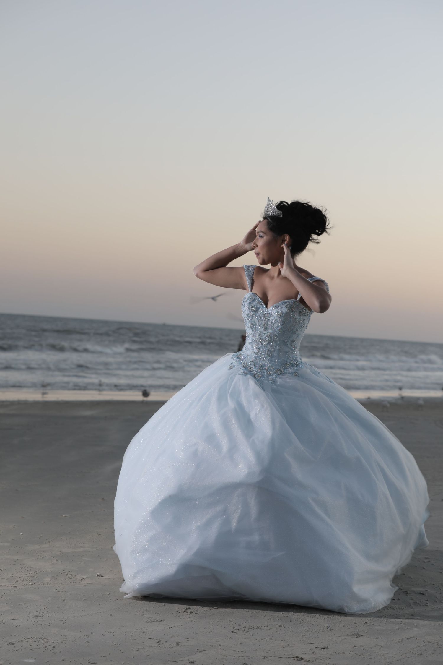 White ballgown with crystal bodice photographed at sunset on sandy beach.