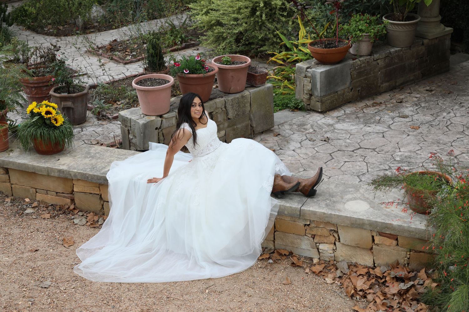 A relaxed bridal portrait on stone garden steps surrounded by terracotta planters.