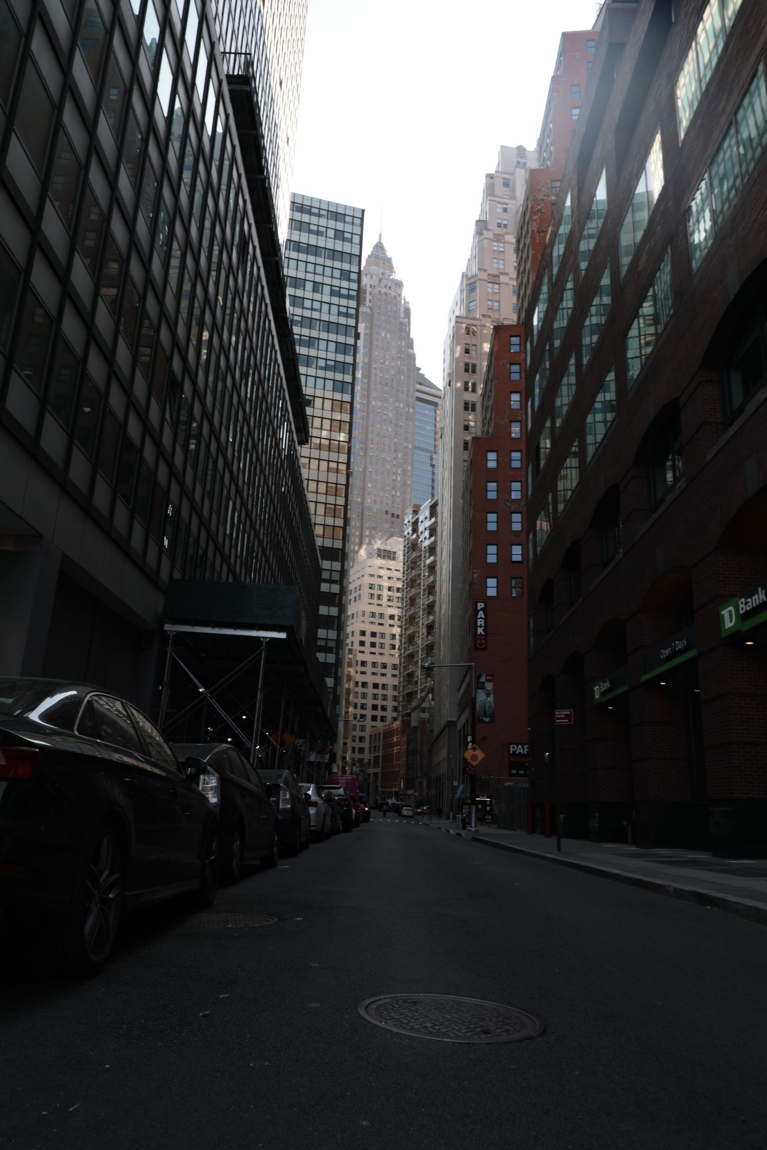 Dark urban street view between tall office buildings and skyscrapers in a downtown business district.