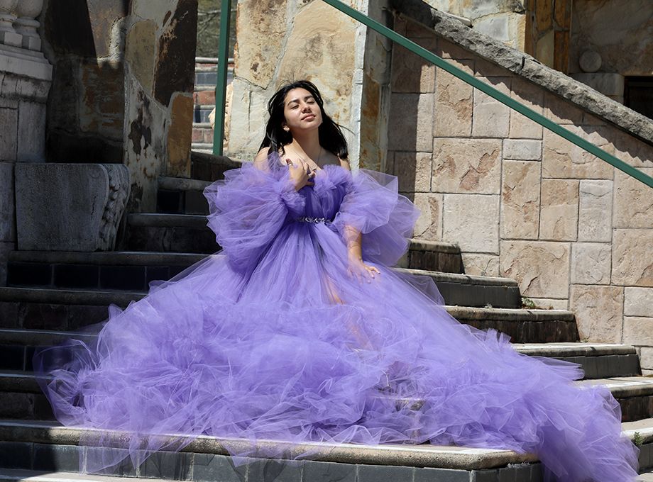 Dramatic purple tulle gown flowing on stone steps during fashion photoshoot.