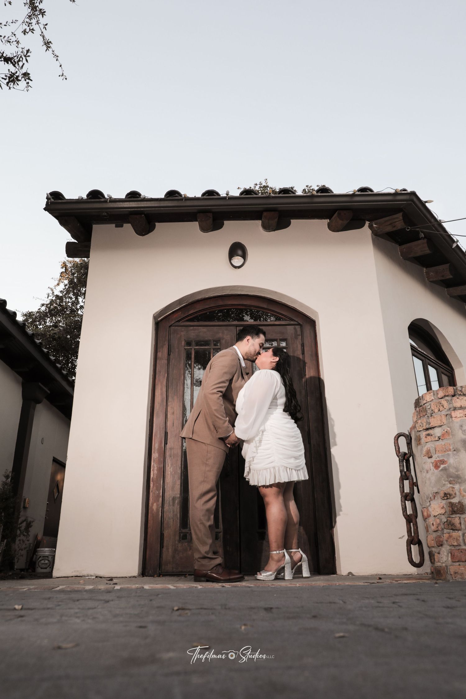 Romantic couple shares an intimate moment in a Spanish-style doorway.
