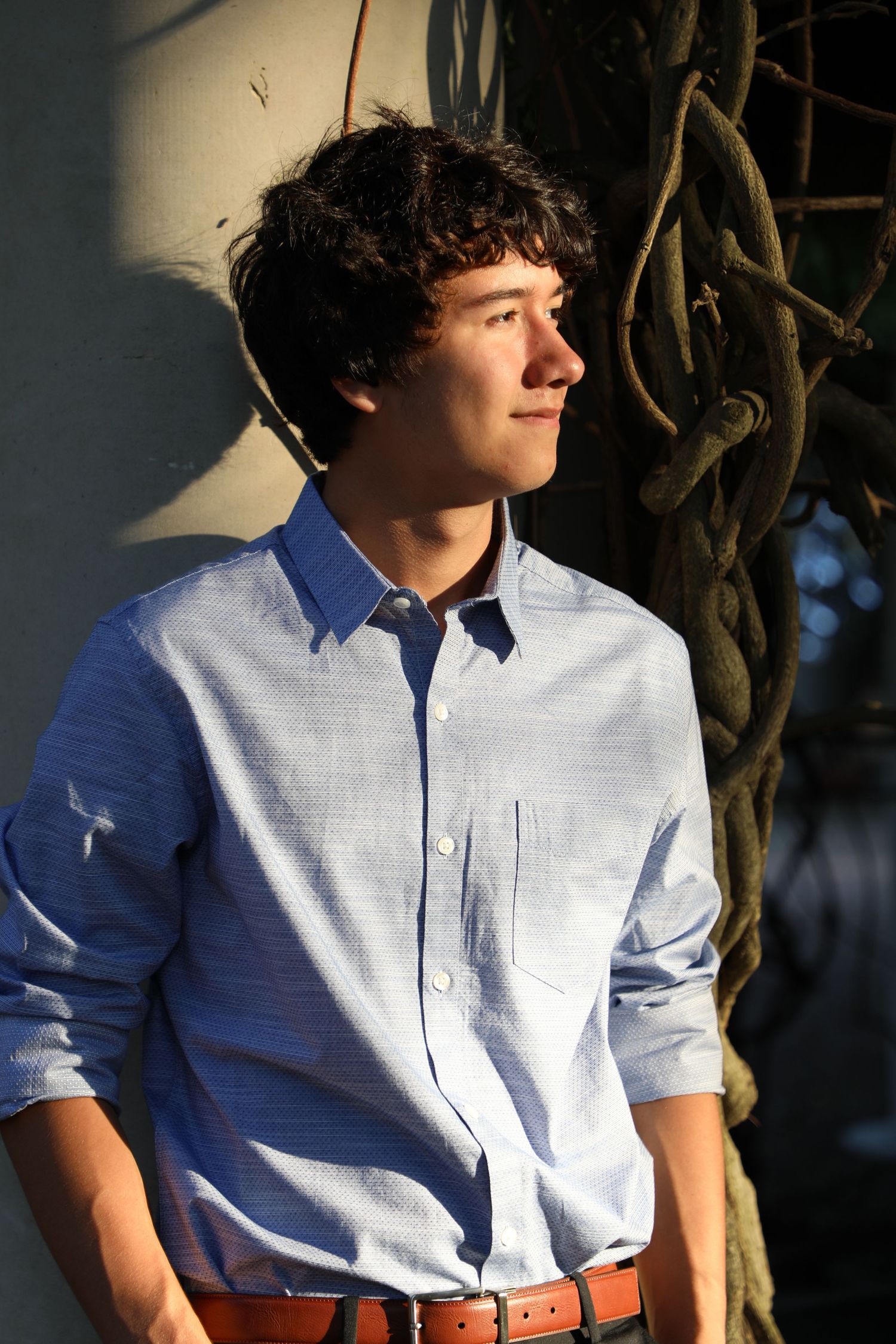 Portrait in natural lighting against vine-covered wall background.