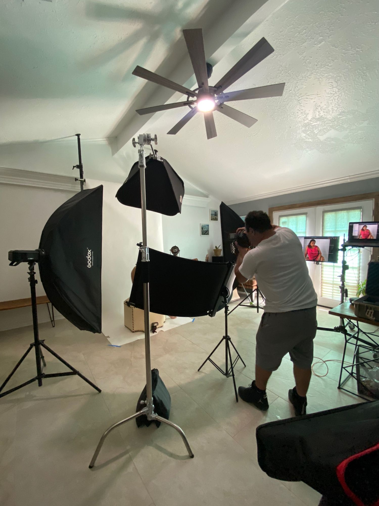 Professional photography studio setup with softboxes, lighting equipment and ceiling fan.