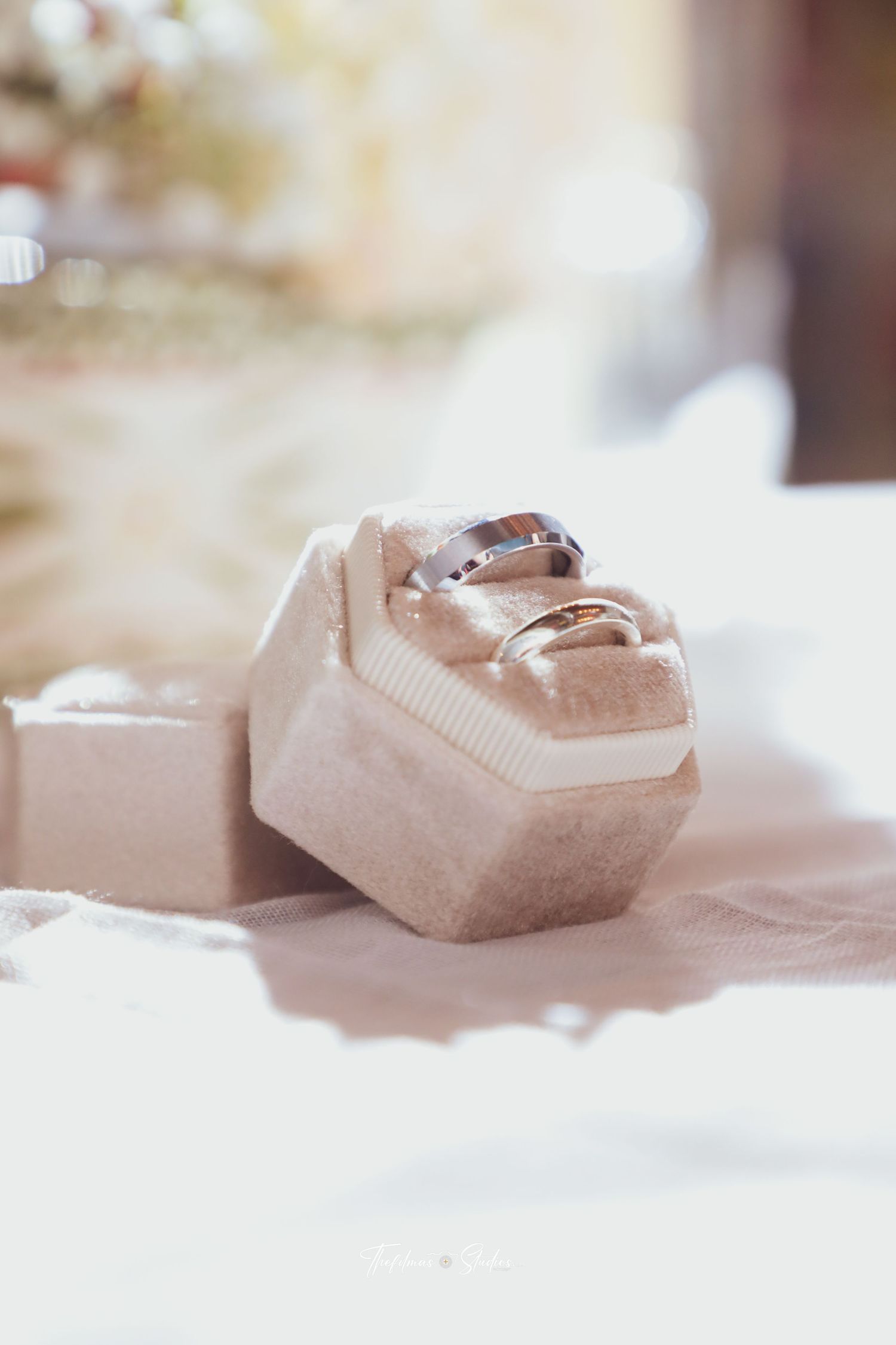 Wedding rings displayed on a plush velvet ring box in soft lighting.