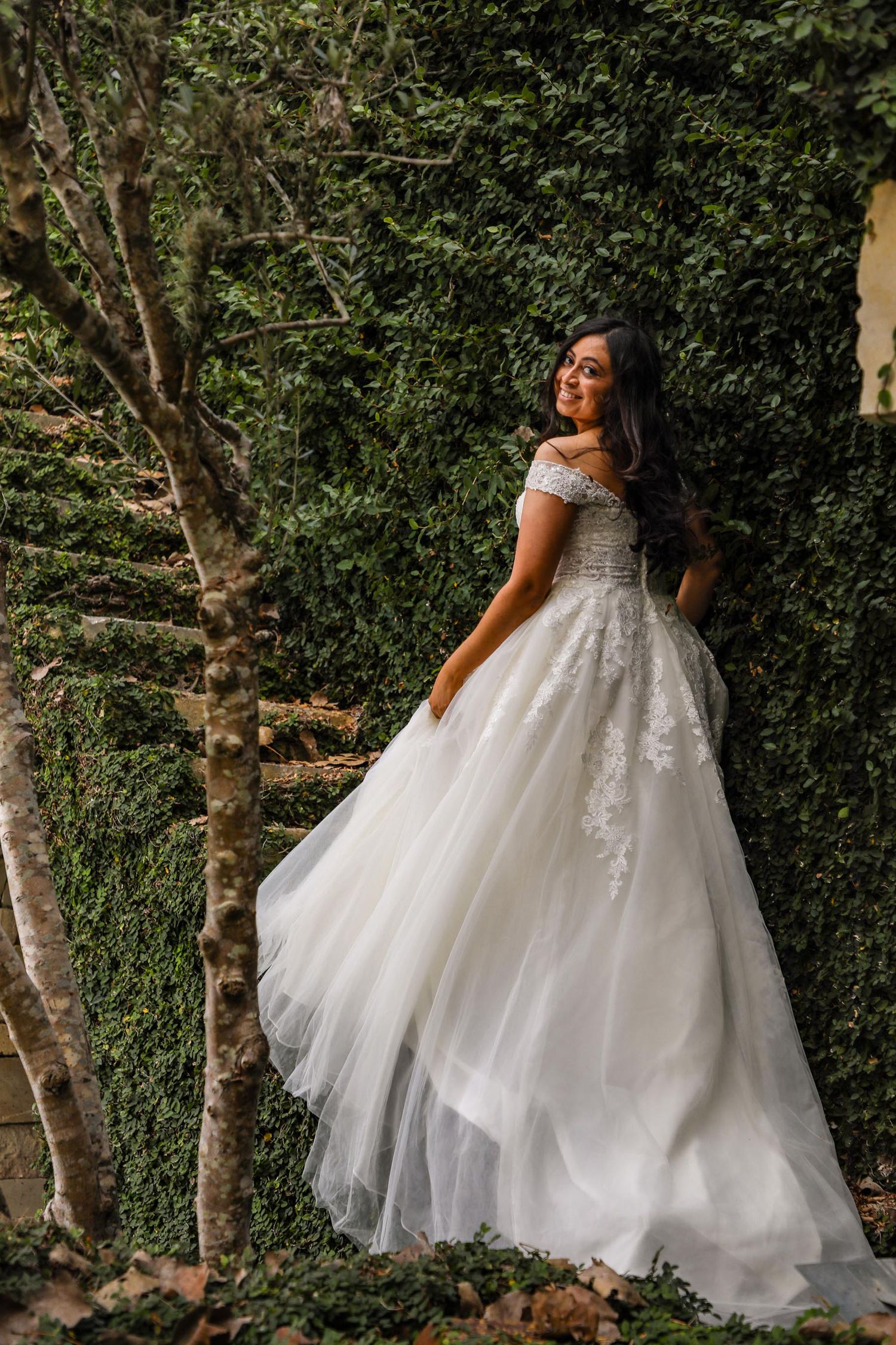 A princess ballgown wedding dress with delicate lace details photographed in a lush garden setting.