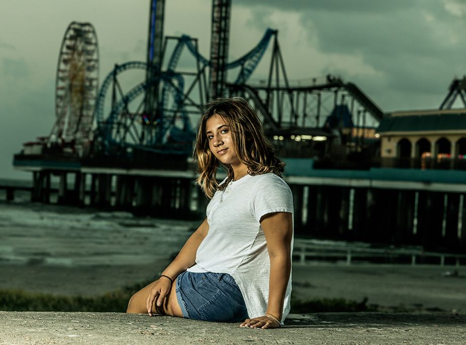Casual portrait with amusement park rides and ferris wheel in background.
