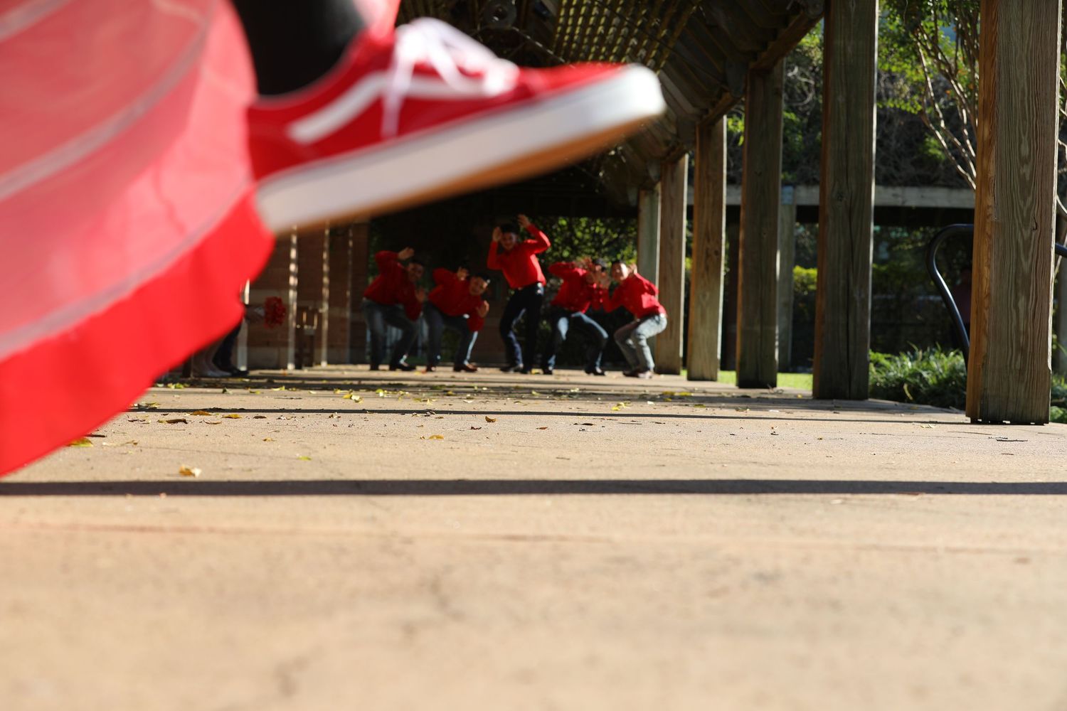 A blurred red sneaker in foreground with people sitting on benches in the background.