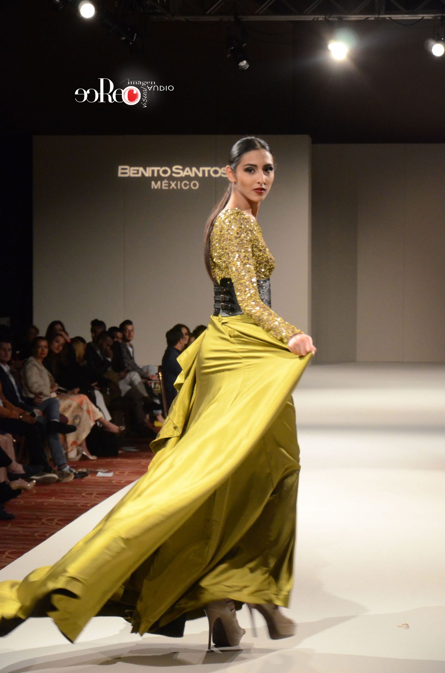 Model showcasing dramatic yellow evening gown on fashion runway.