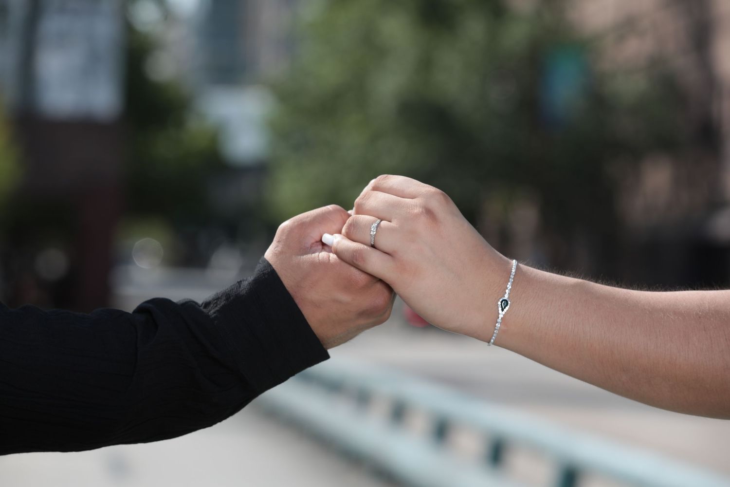 Close-up of holding hands showing engagement ring and bracelet.