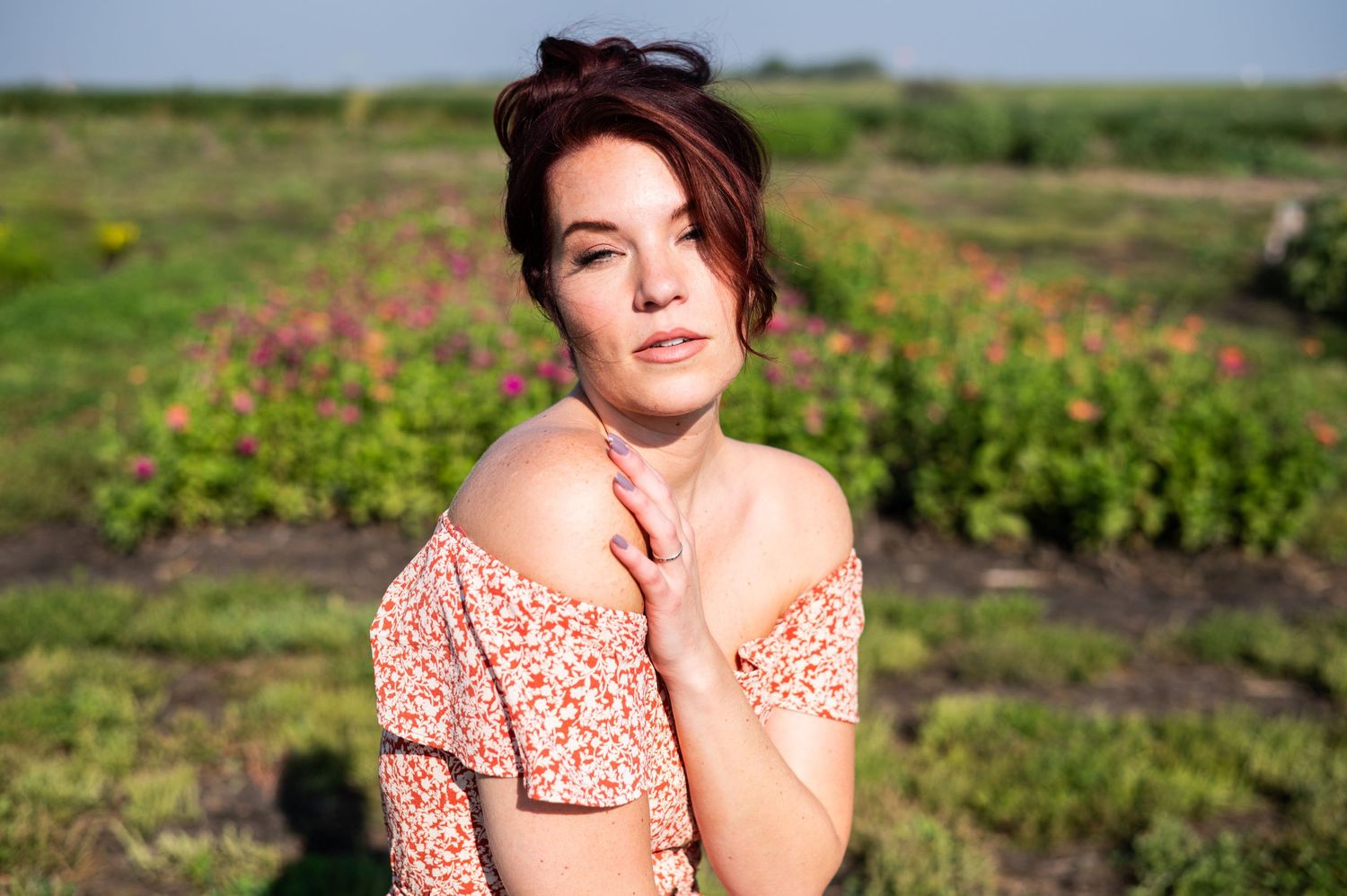 Dreamy outdoor portrait in a peach floral dress against a field of flowers.