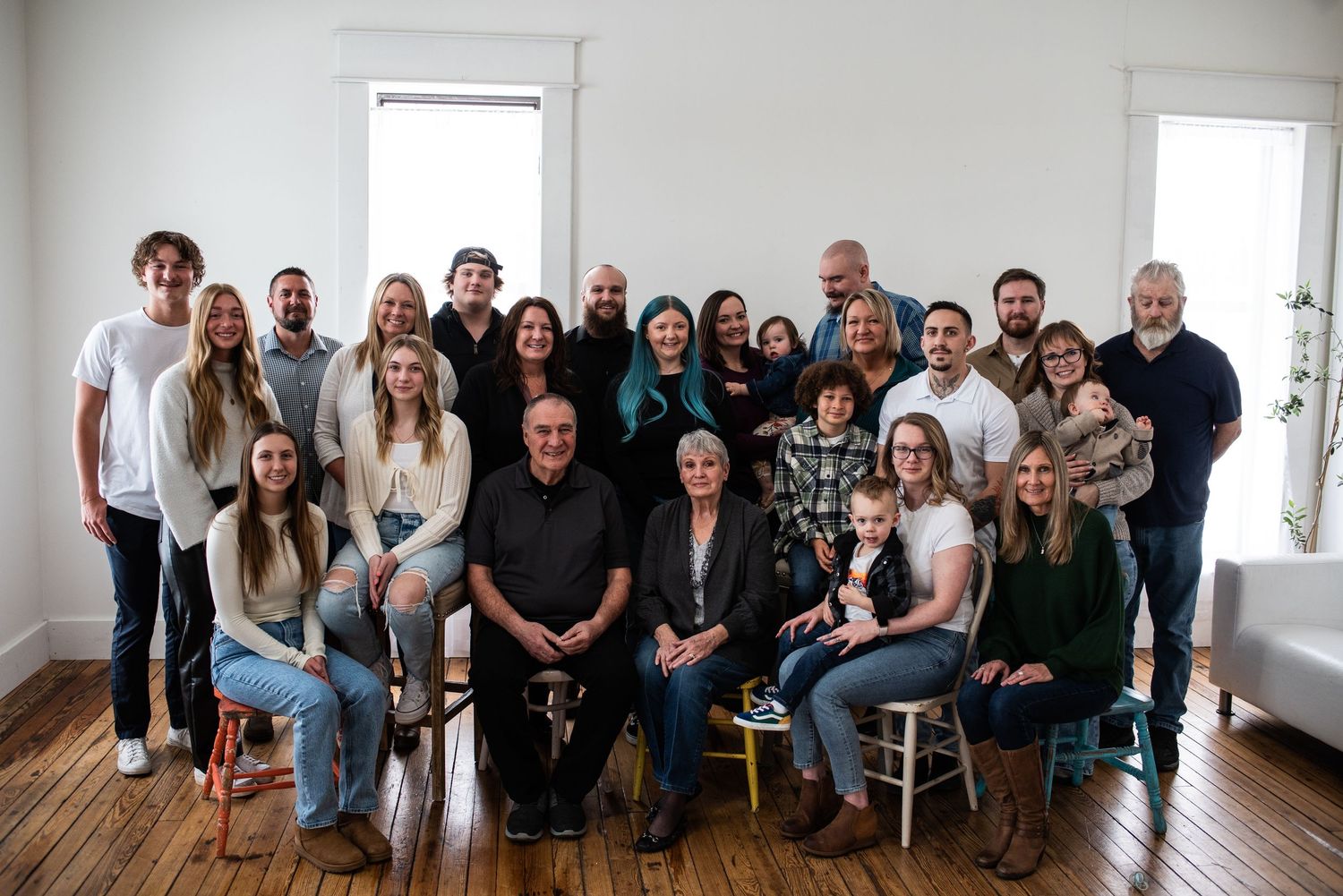 Large family group portrait with multiple generations seated together indoors.