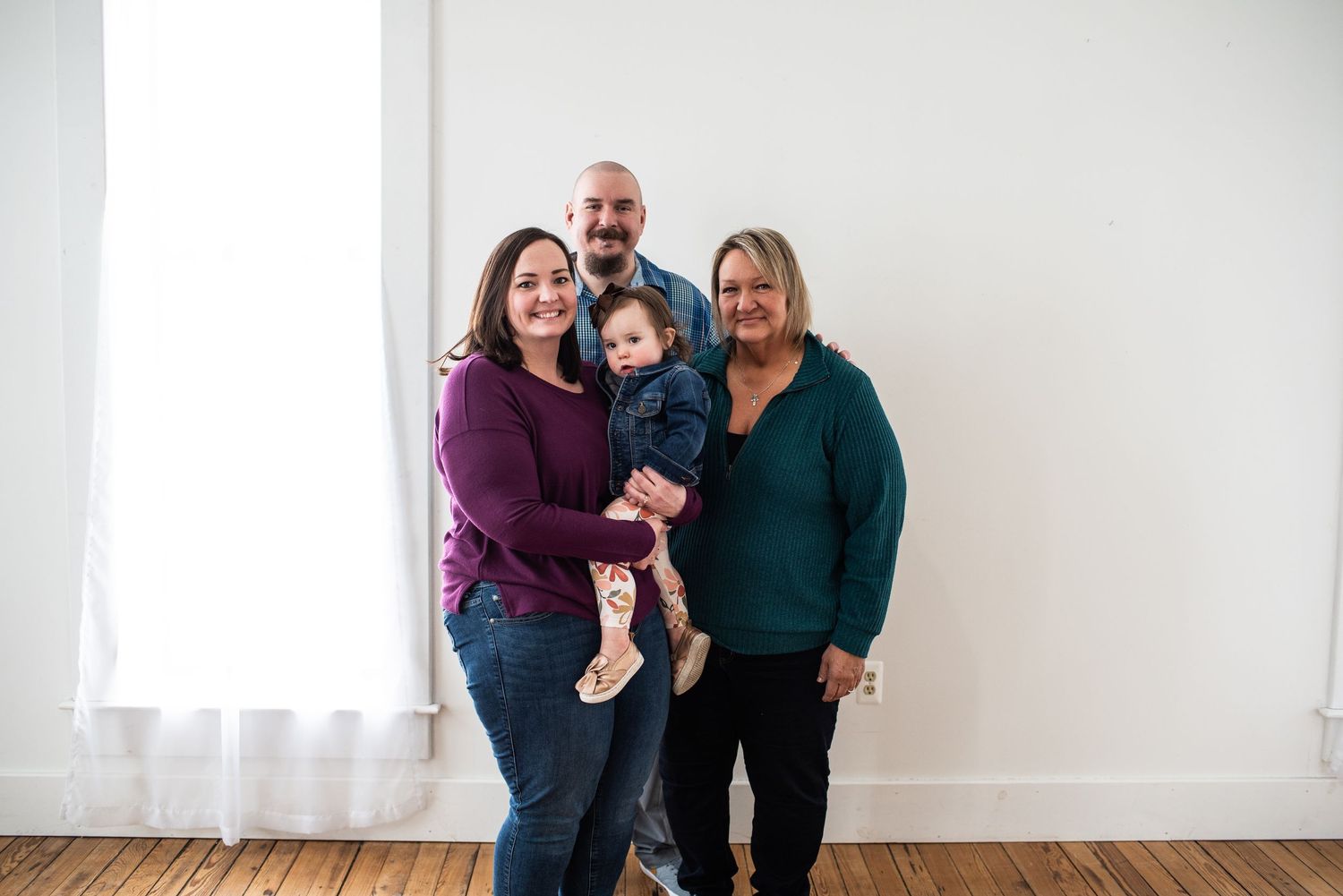 Group photo of people gathered together against white wall in bright indoor setting.