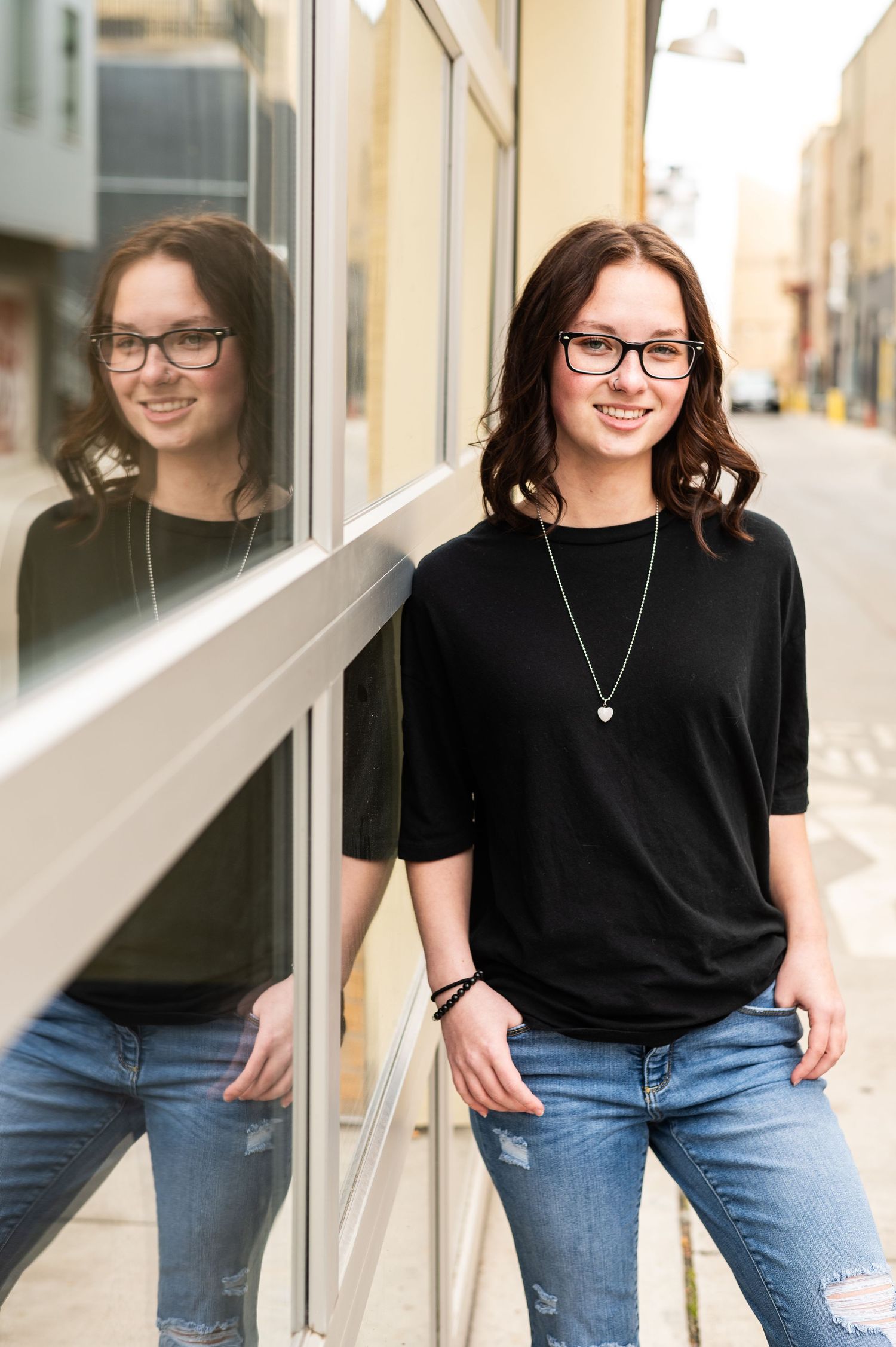 Portrait series against modern building with casual black t-shirt and denim outfit.