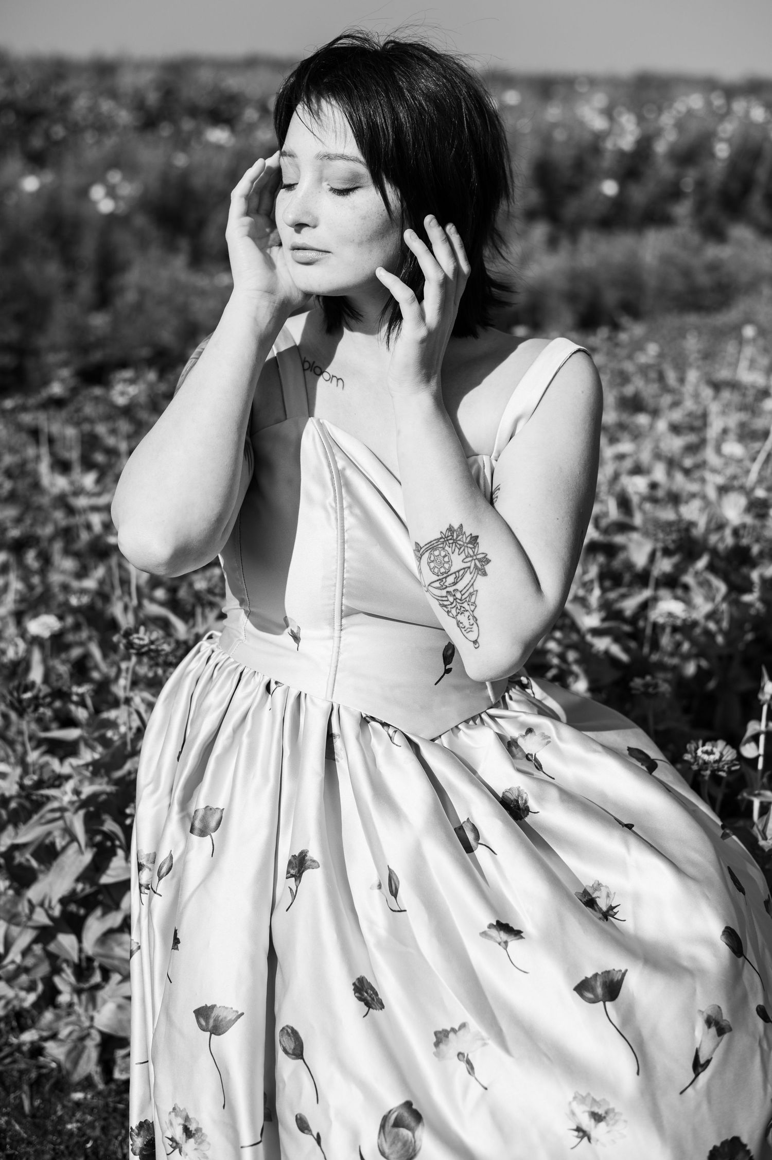 Black and white portrait of person in vintage dress touching their face.