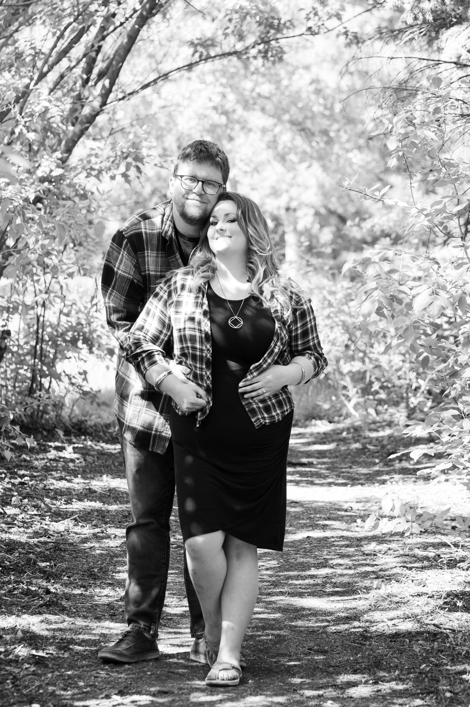 Black and white photos of a couple laughing together on a wooded nature trail.