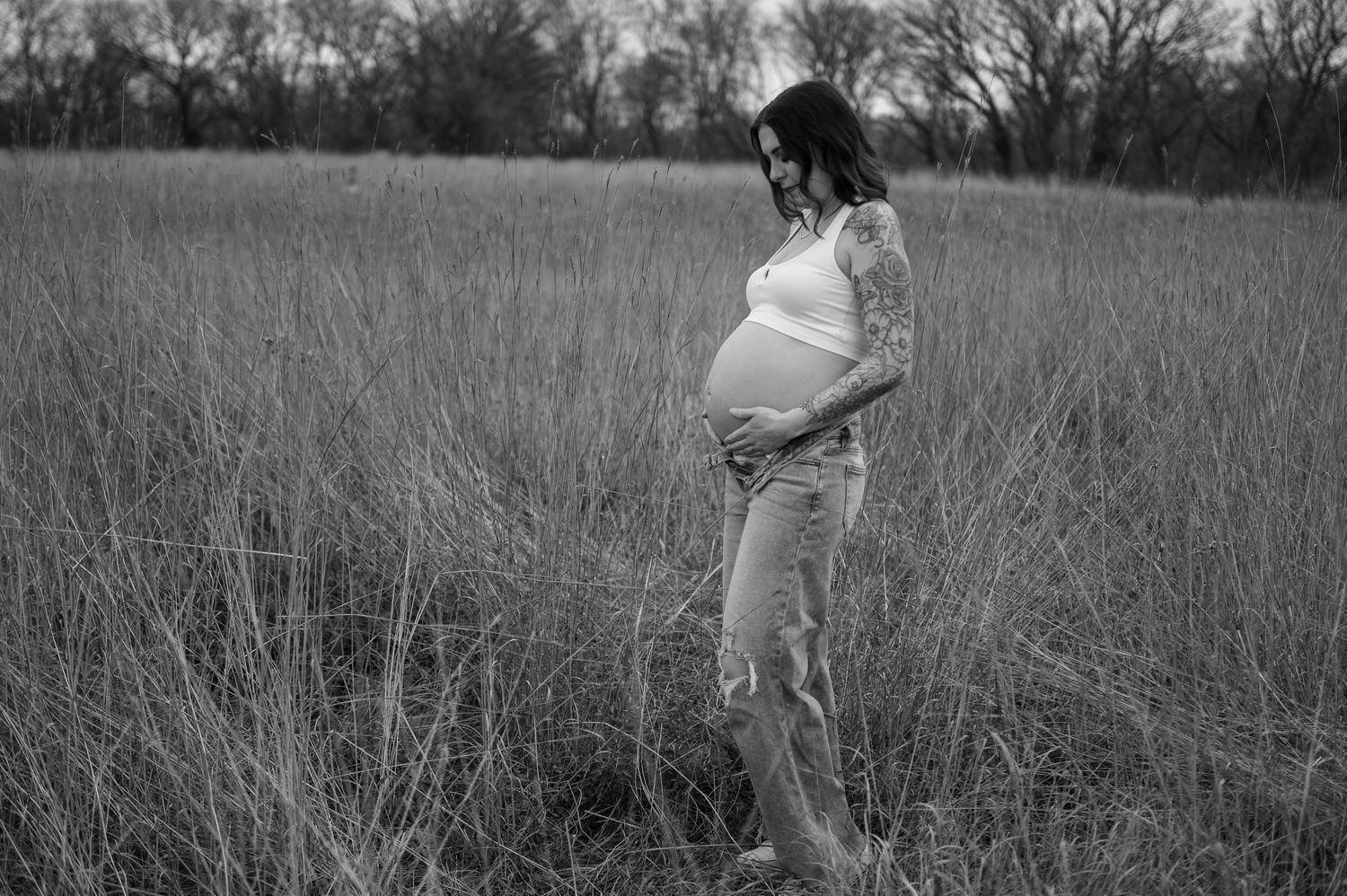 Outdoor maternity photos in tall grass field during golden hour.