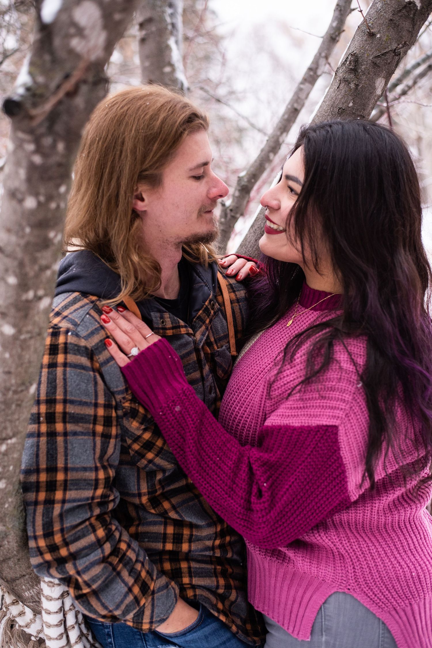 Two people share tender moments while wearing plaid and pink sweaters against a winter backdrop.