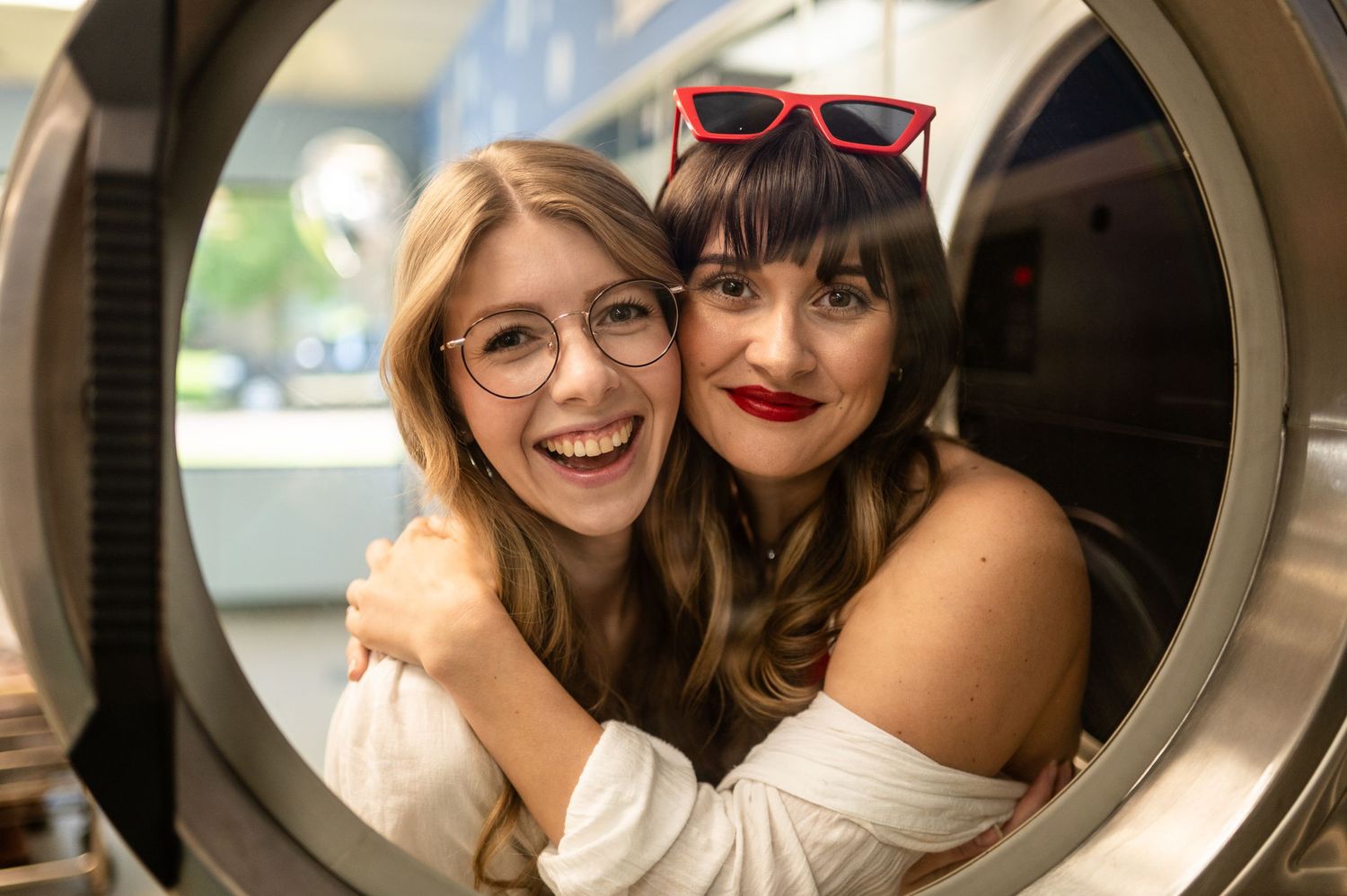 Two friends smile together through circular window frame.