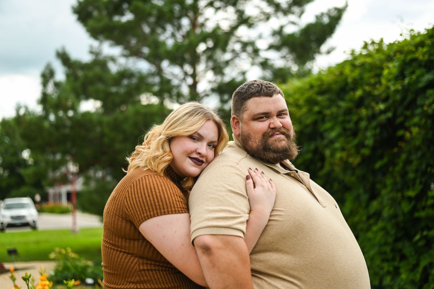 Couple shares intimate moments while sitting together outdoors on a green summer day.