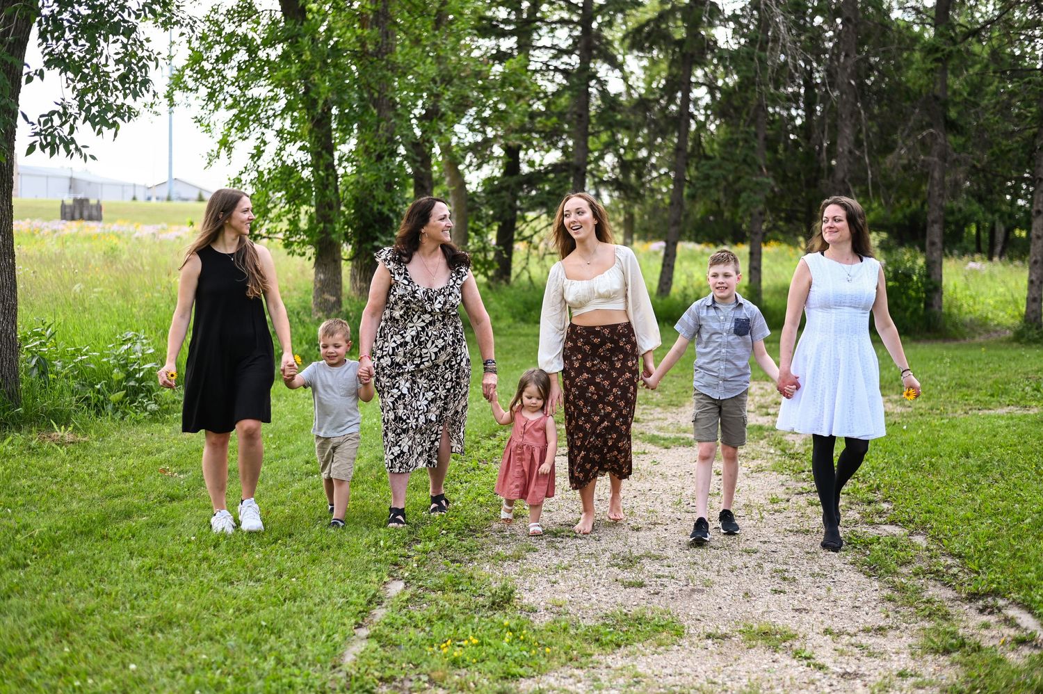 Group of people walking together on a tree-lined dirt path in nature.
