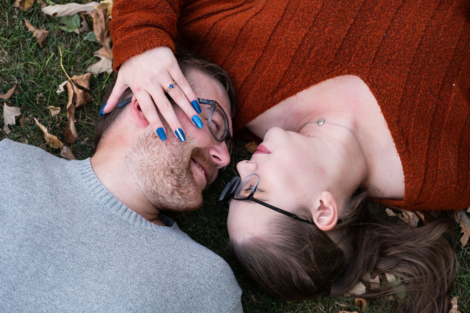 Couple lying on autumn leaves sharing an intimate moment.