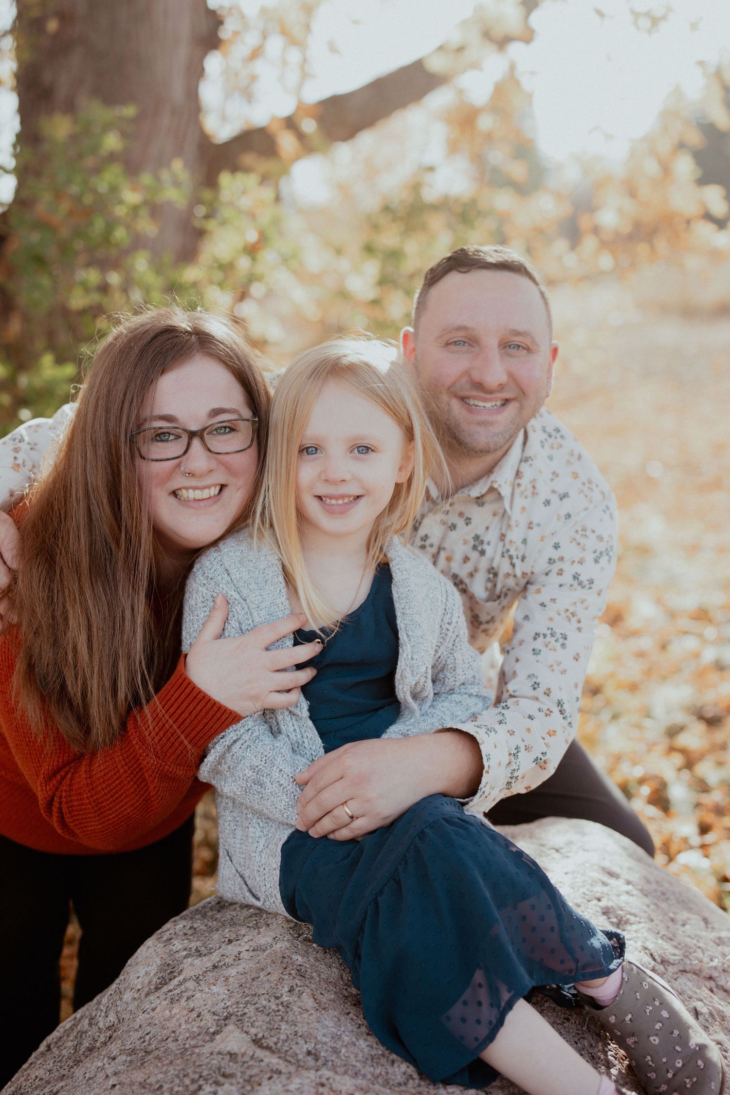 Family photo session with people on rocks surrounded by fall foliage.