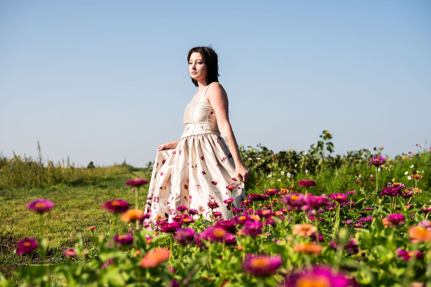 Person in flowing dress twirls among vibrant pink wildflowers.