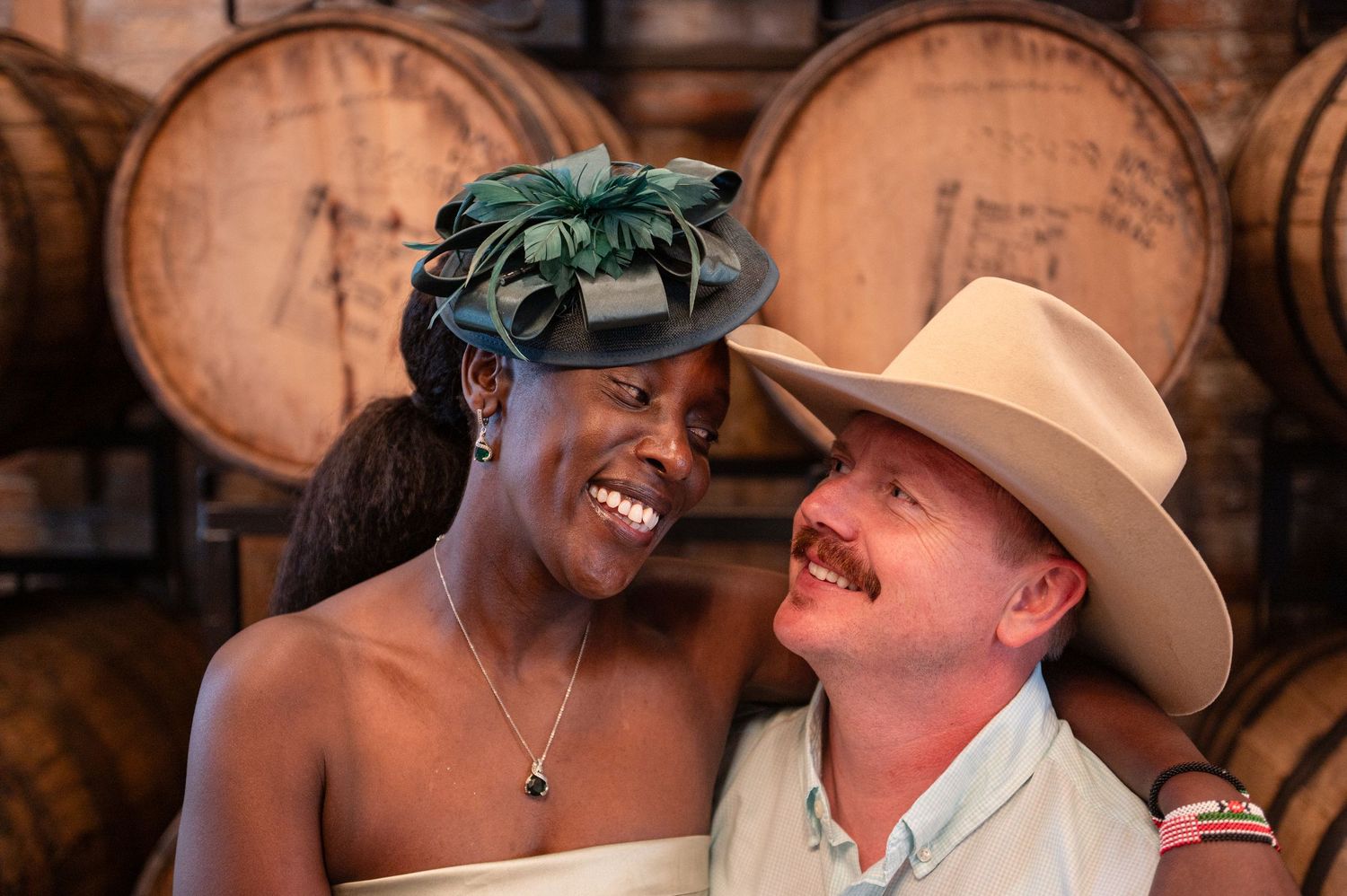 Two people share an affectionate moment together while smiling and laughing in a dimly lit setting.