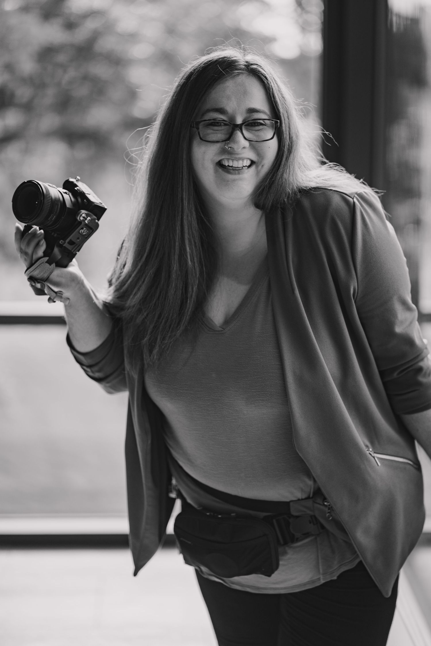 Black and white portraits of photographer holding camera in casual business attire.