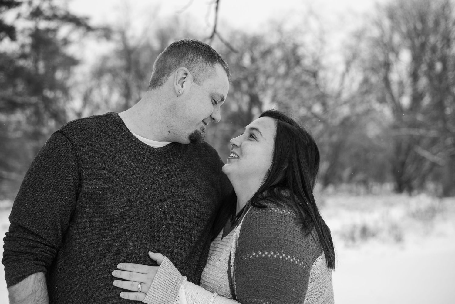 A couple shares an intimate moment against a snowy winter background.